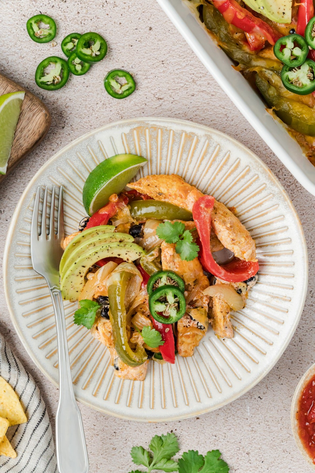 A plate with a serving of fajita casserole, garnished with avocado.