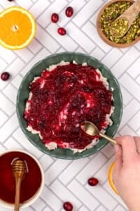 Spreading cranberry sauce on top of a layer of soft cheese.