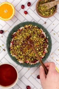 Drizzling hot honey on a bowl of gournay cheese dip with cranberry and pistachio.