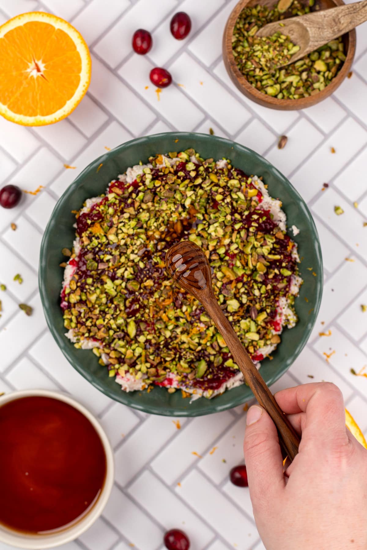 Drizzling hot honey on a bowl of gournay cheese dip with cranberry and pistachio.
