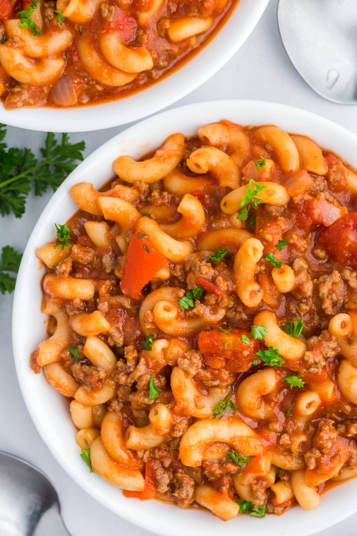 A bowl filled with elbow macaroni, ground beef, and tomato sauce.