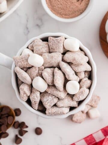 A mug of muddy buddies, dotted with random mini marshmallows.