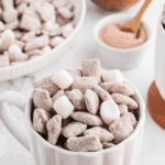 A mug full of chex snack mix, dotted with mini marshmallows.