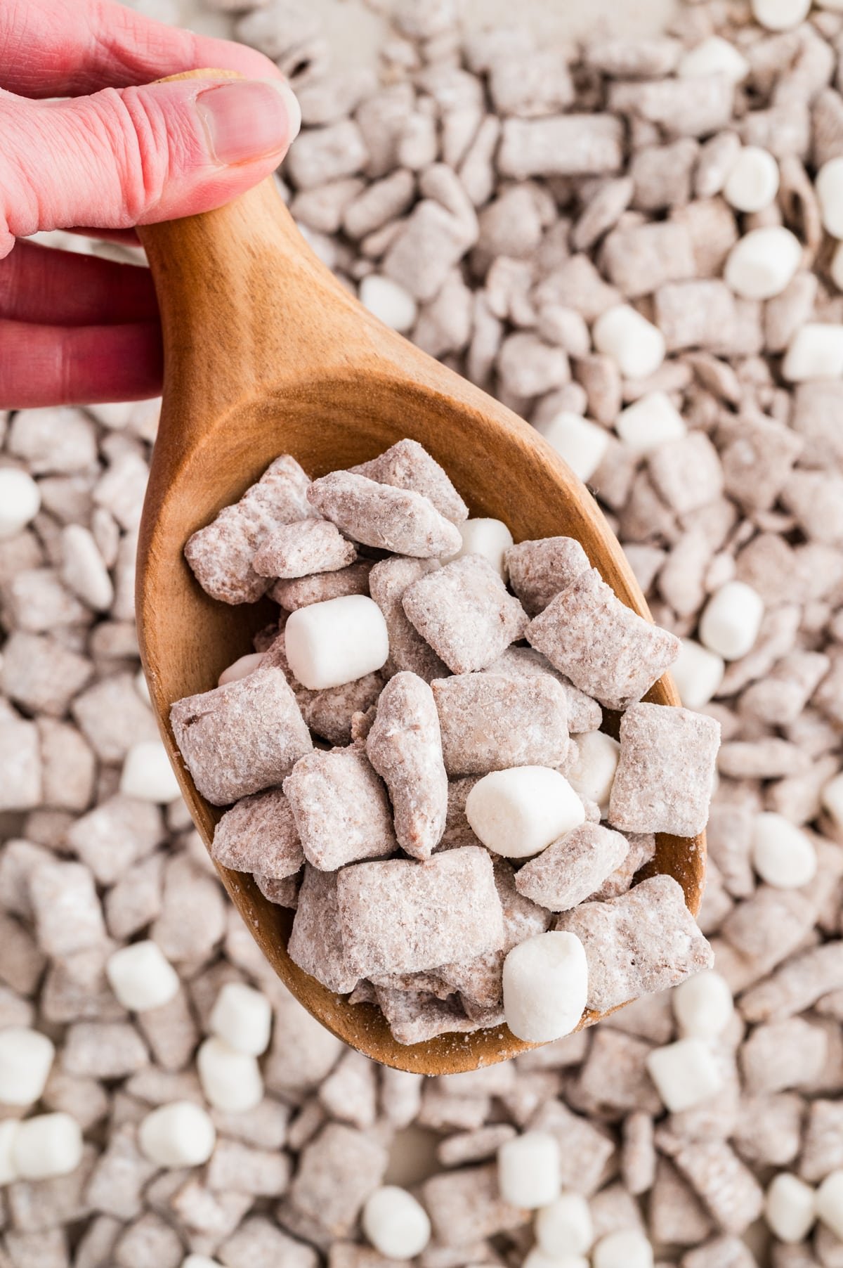 Scooping muddy buddies from a larger amount.