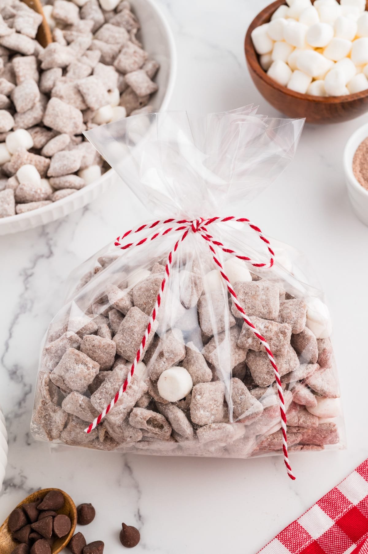 A cellophane gift bag filled with muddy buddies and tied with a decorative string.