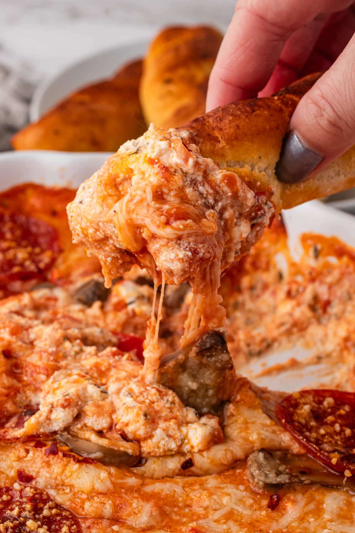 Dipping a breadstick into a gooey pizza dip with cream cheese.