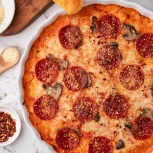 A bubbly baked pepperoni pizza dip, with breadsticks ready to dip in.