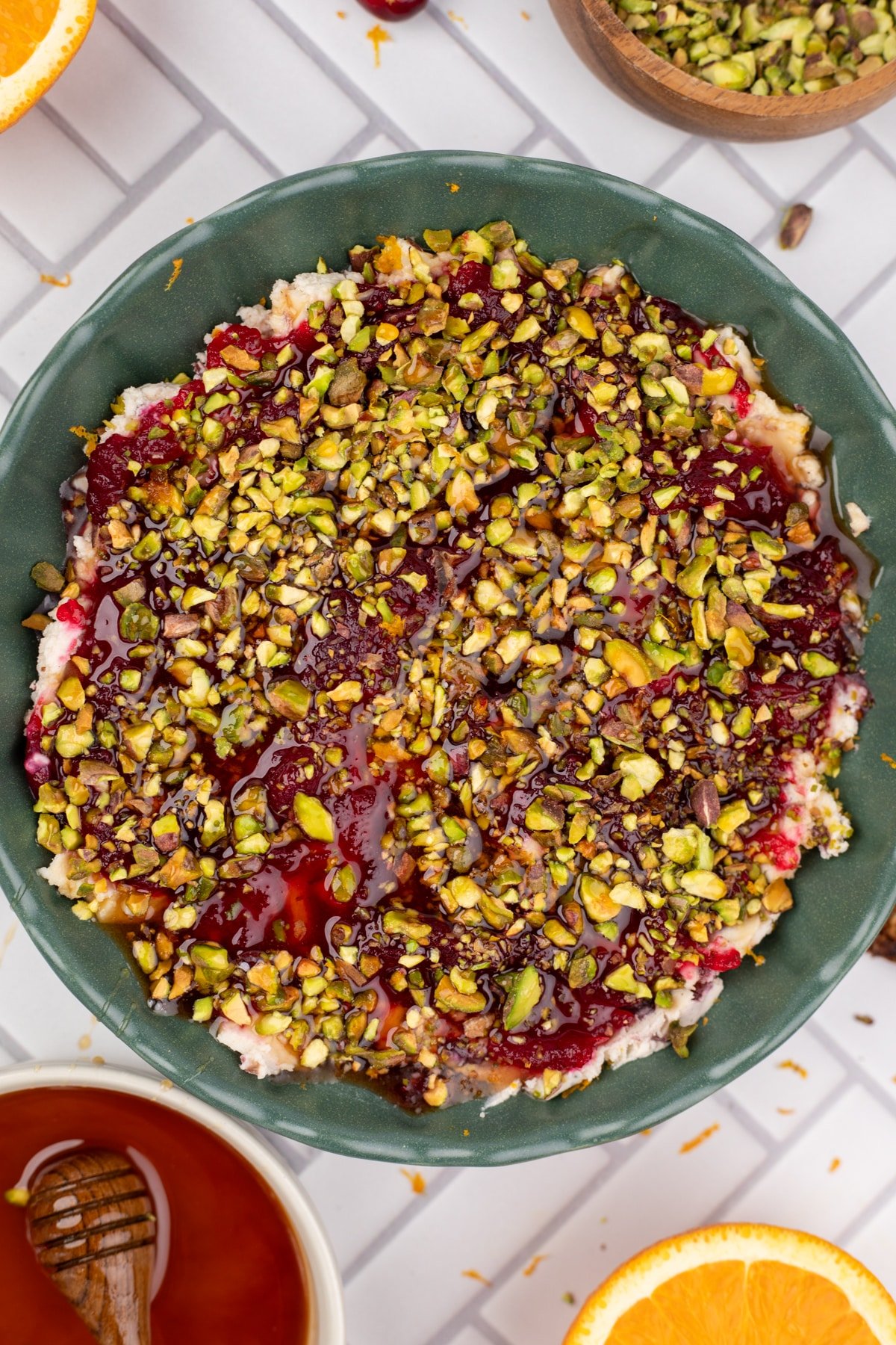 A bowl of boursin dip with cranberry sauce and pistachios.