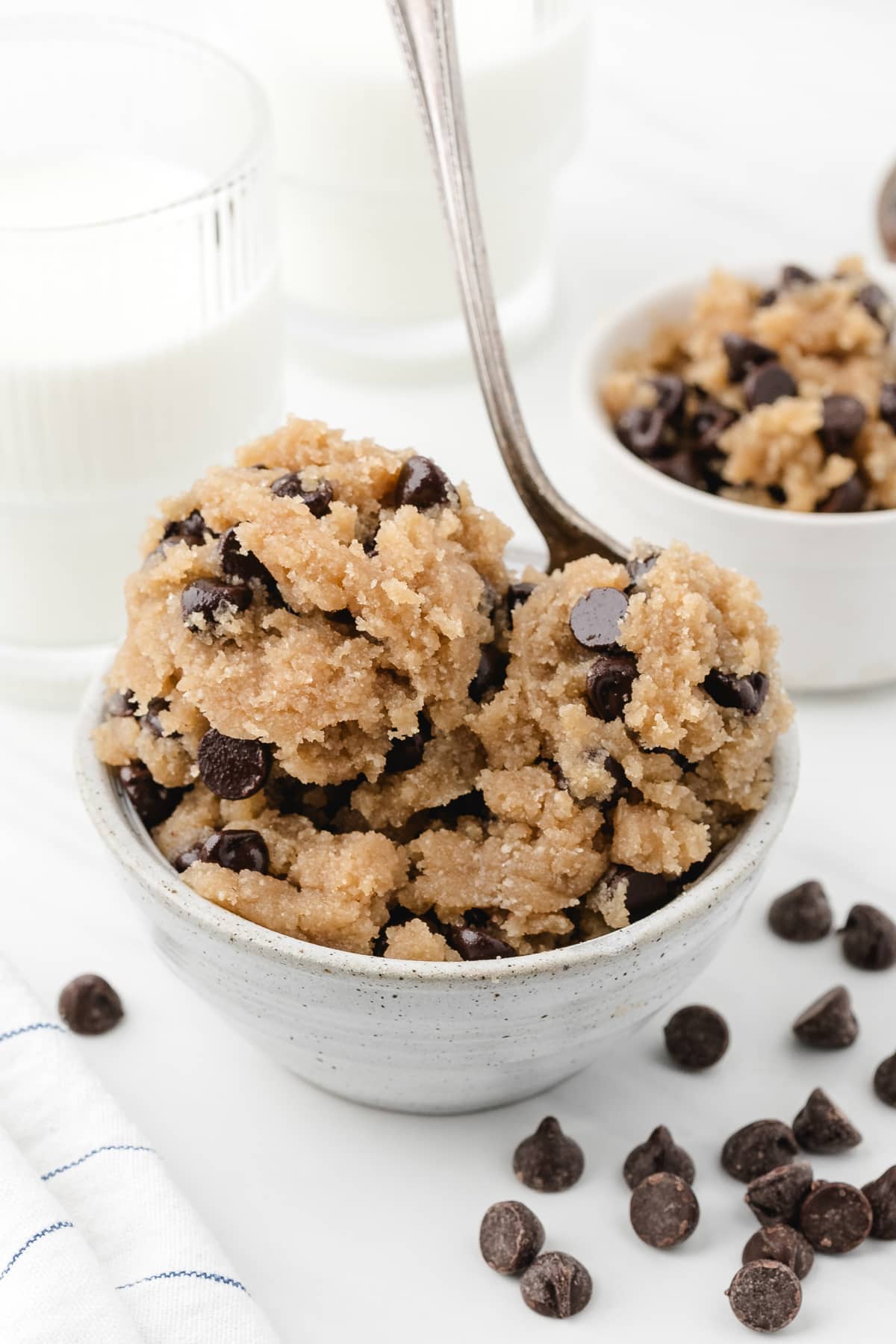 A bowl of chocolate chip cookie dough with a spoon sticking out of it.