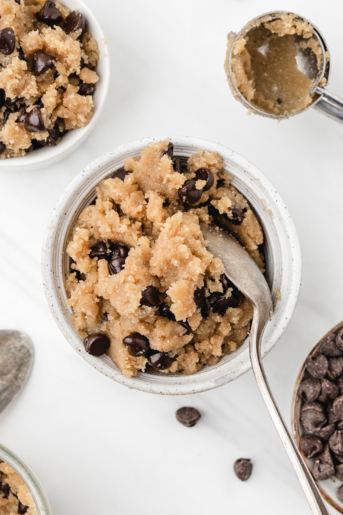 A small bowl of cookie dough with a spoon in it.