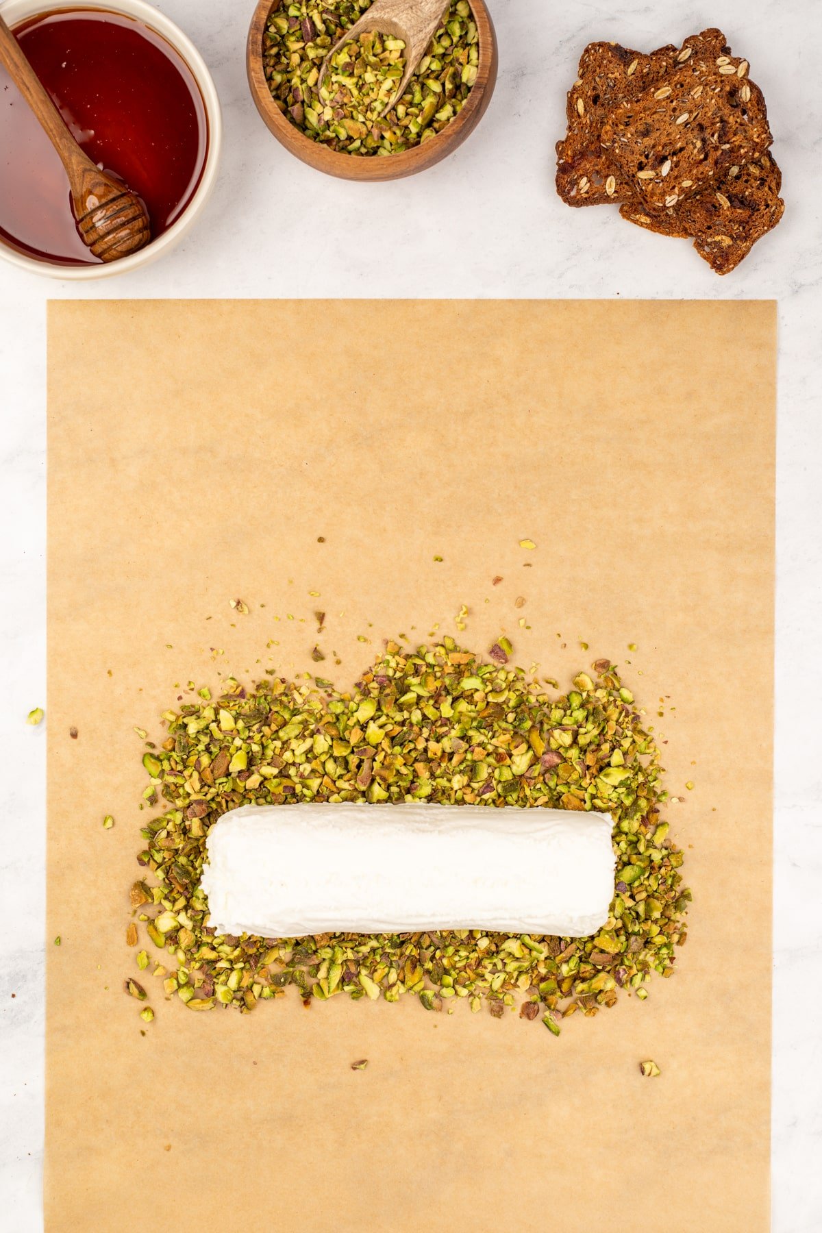 A log of goat cheese placed on top of a gentle mound of crushed pistachios.