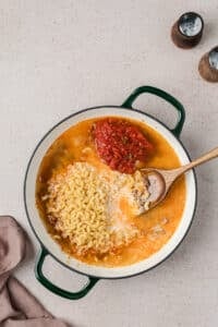 Adding macaroni, broth, milk, and salsa to a skillet.