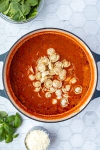 A tomato based soup in a Dutch oven with added tortellini pasta.