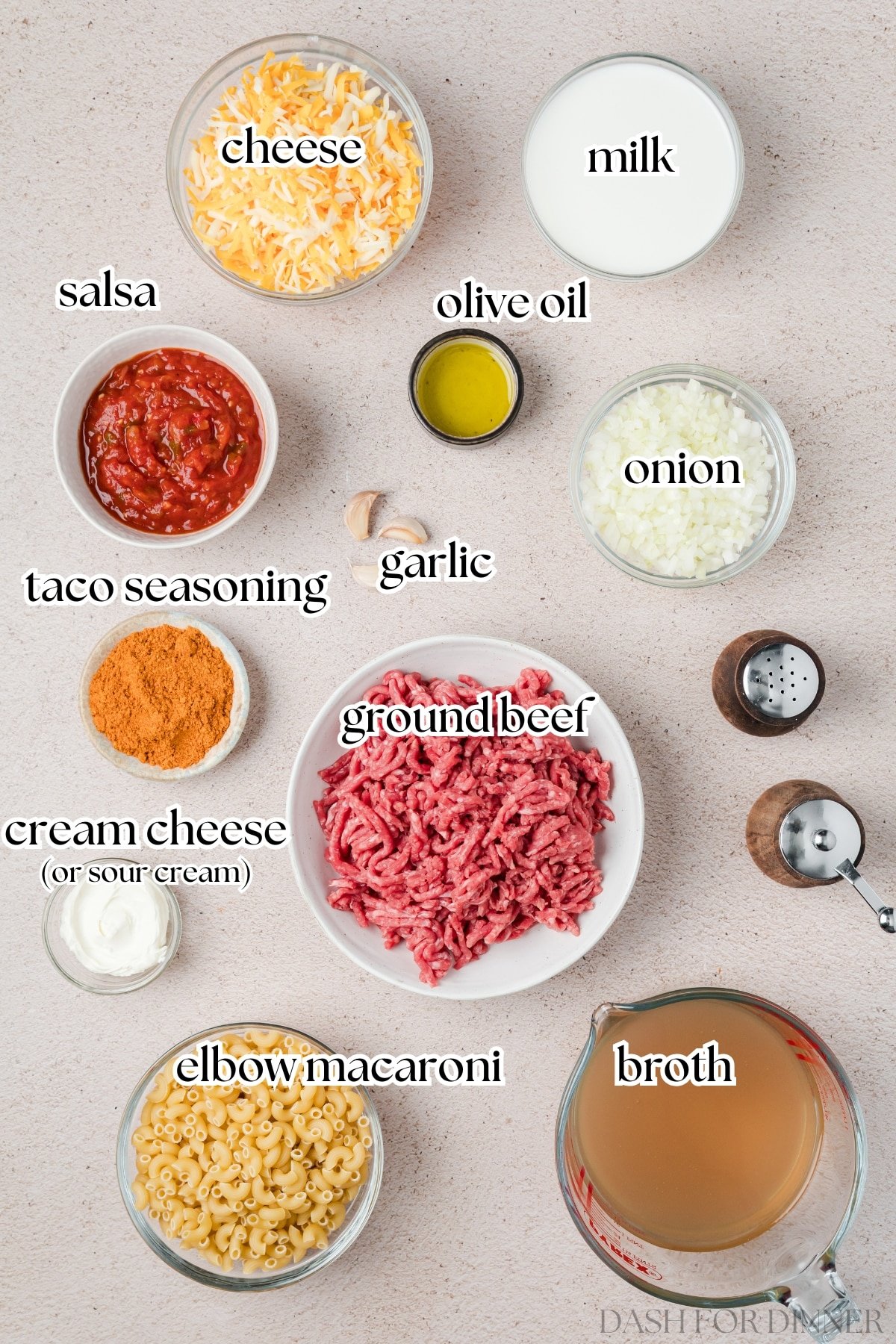 The ingredients needed to make taco mac and cheese, including pasta, ground beef, and broth.