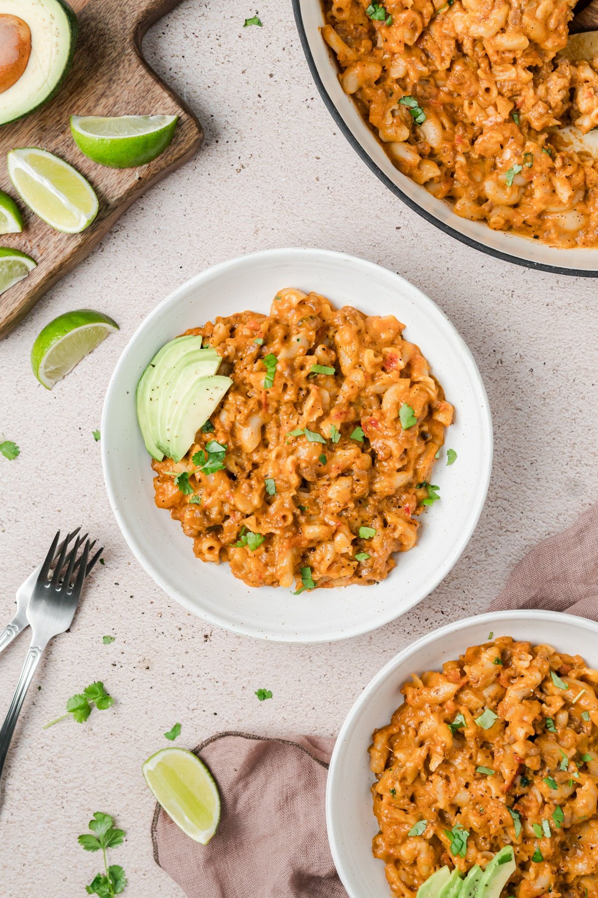A bowl of macaroni and cheese garnished with avocado and cilantro.