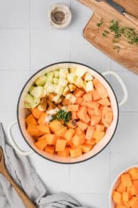 A dutch oven filled with sweet potato and apple cubes.