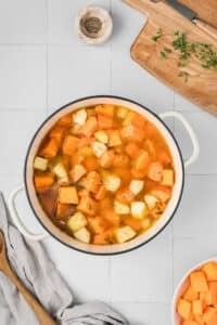 A dutch oven filled with cubed sweet potato, apple, and broth.