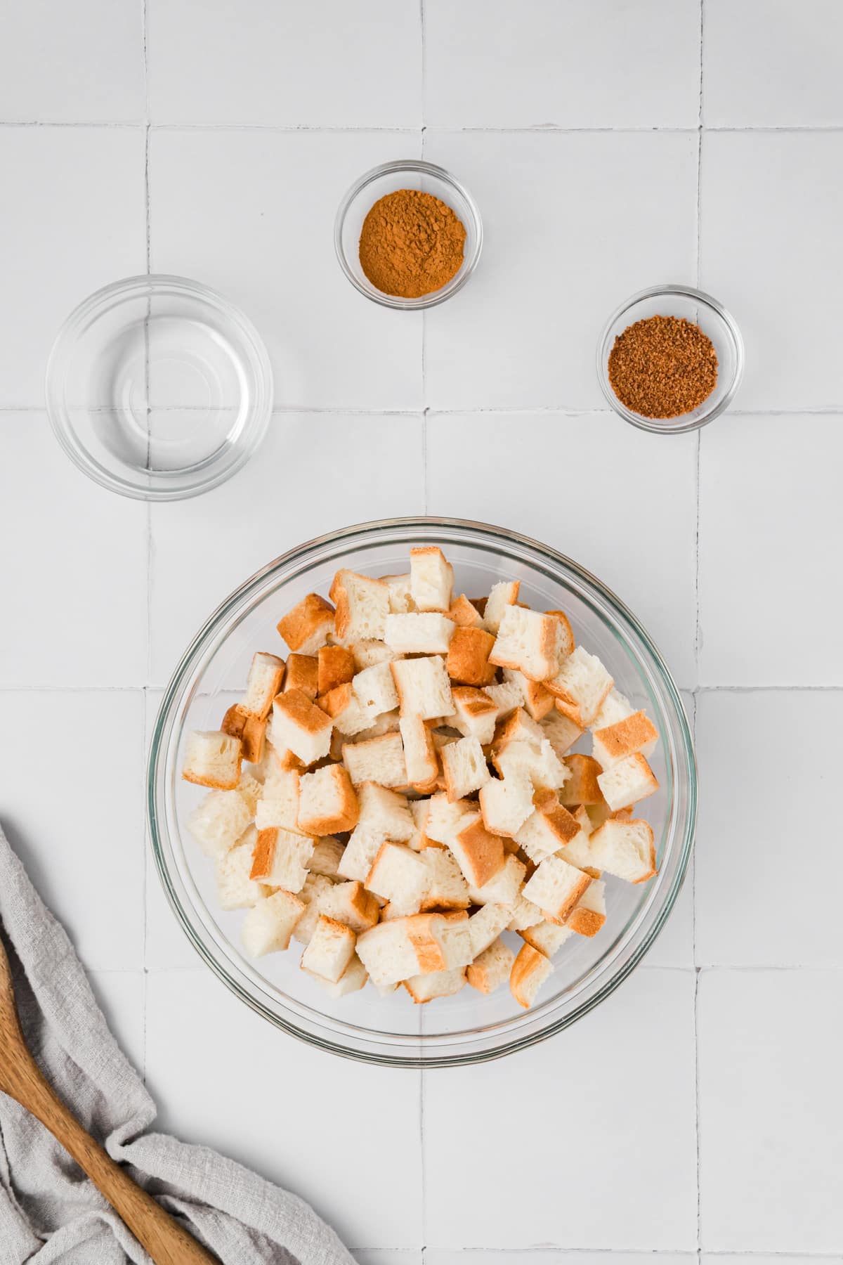 A bowl of bread cubes with a few small pinch bowls of ingredients around the side.