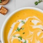 A bowl of soup with a drizzle of coconut milk on the surface.