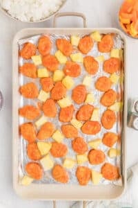 A sheet pan filled with chicken nuggets and pineapple chunks.