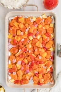 A sheet pan with cooked chicken, pineapple, and bell peppers.