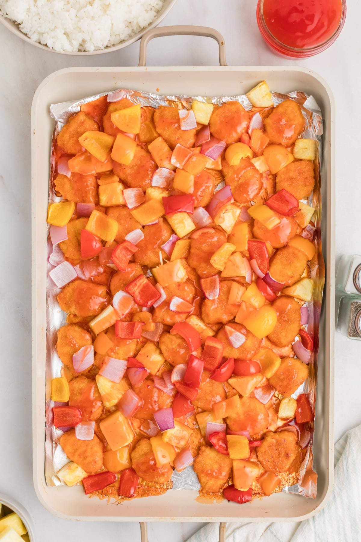 A sheet pan with cooked chicken, pineapple, and bell peppers.
