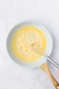Whisking flour into butter to make a roux.
