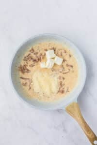 Adding parmesan cheese and cream cheese to a skillet to make a creamy sauce.