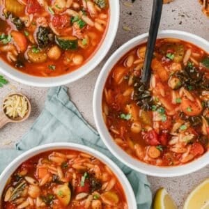 Bowls of soup with vegetables, orzo, and chickpeas.