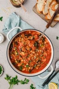 A soup pot filled with vegetable soup with orzo and chickpeas.