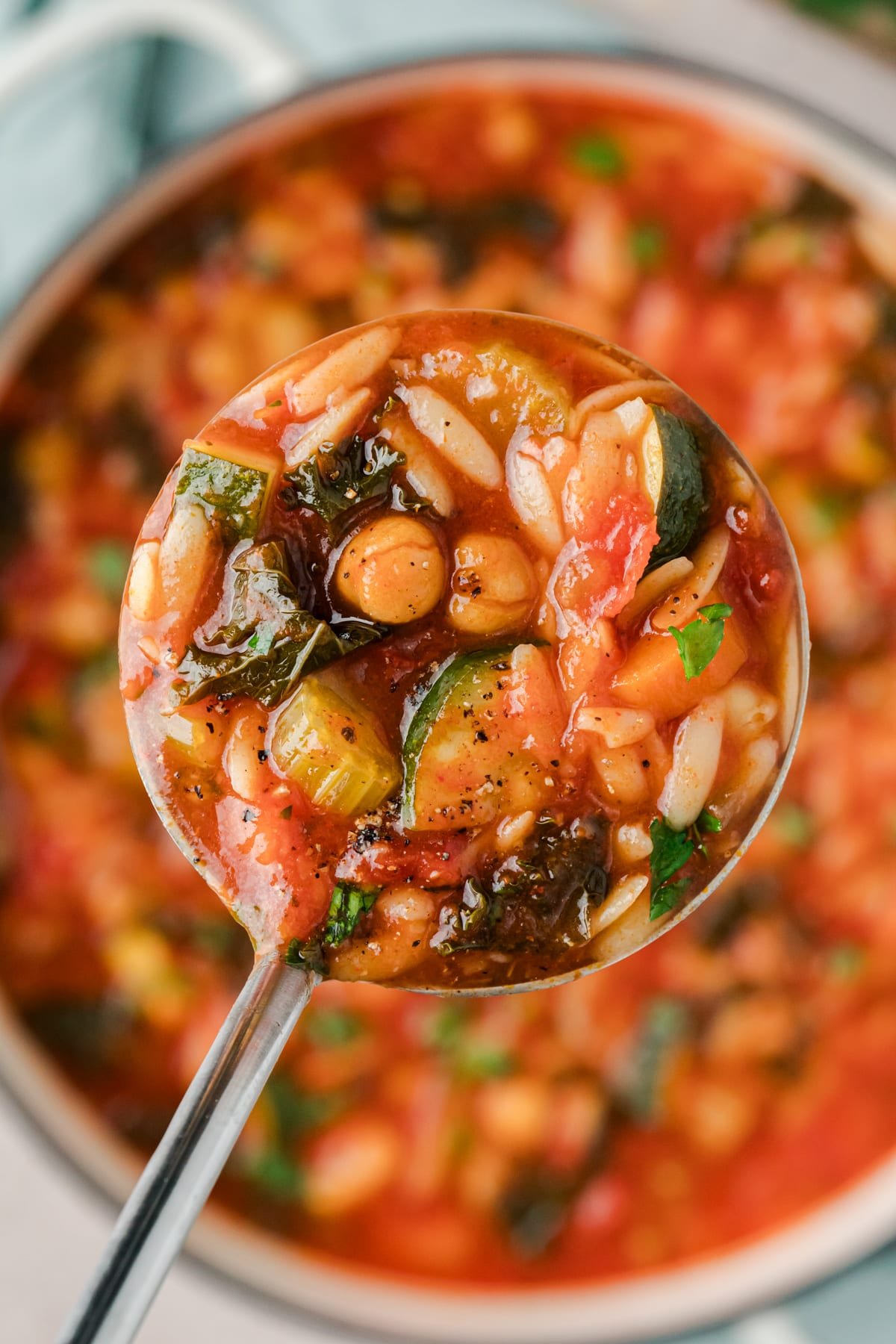A ladle scooping soup from a large Dutch oven.