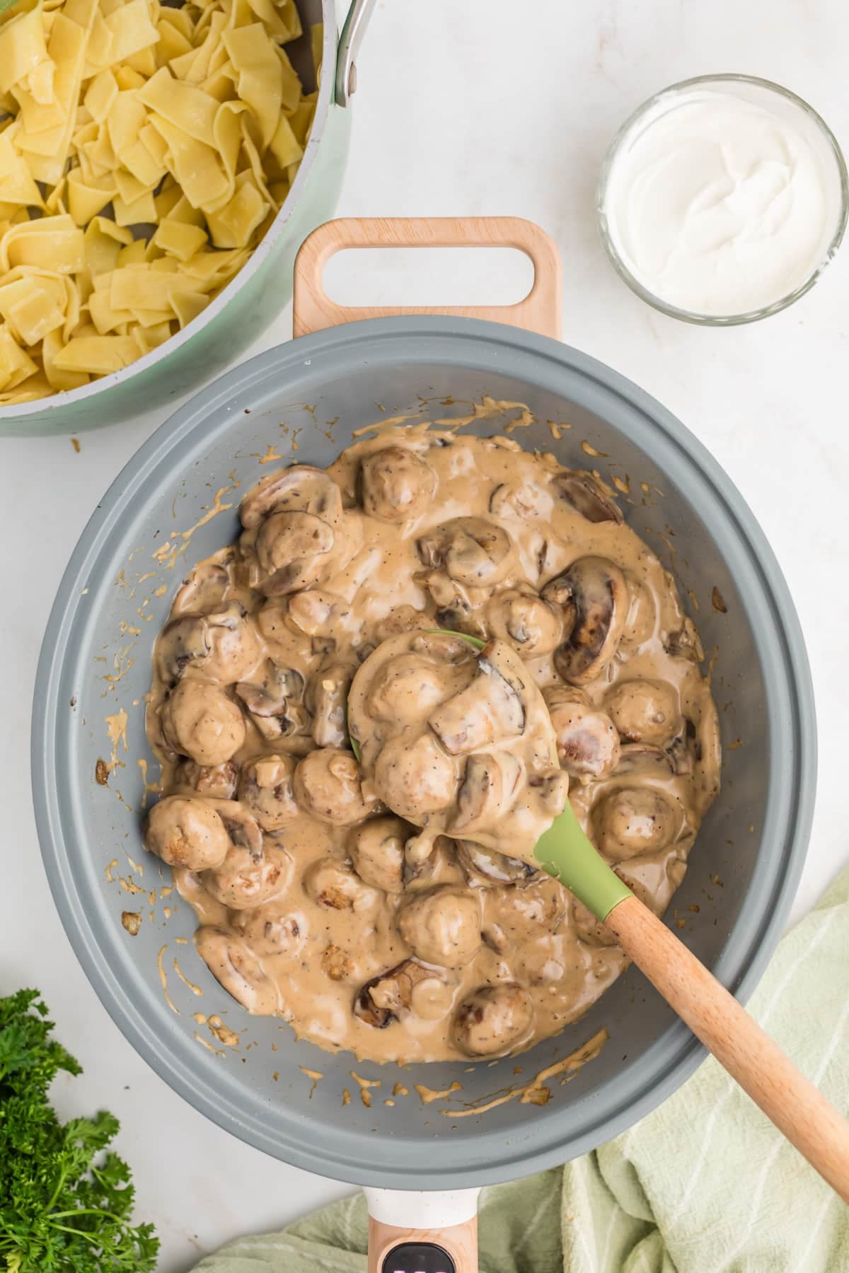 A large skillet filled with mushroom cream sauce and cooked meatballs.