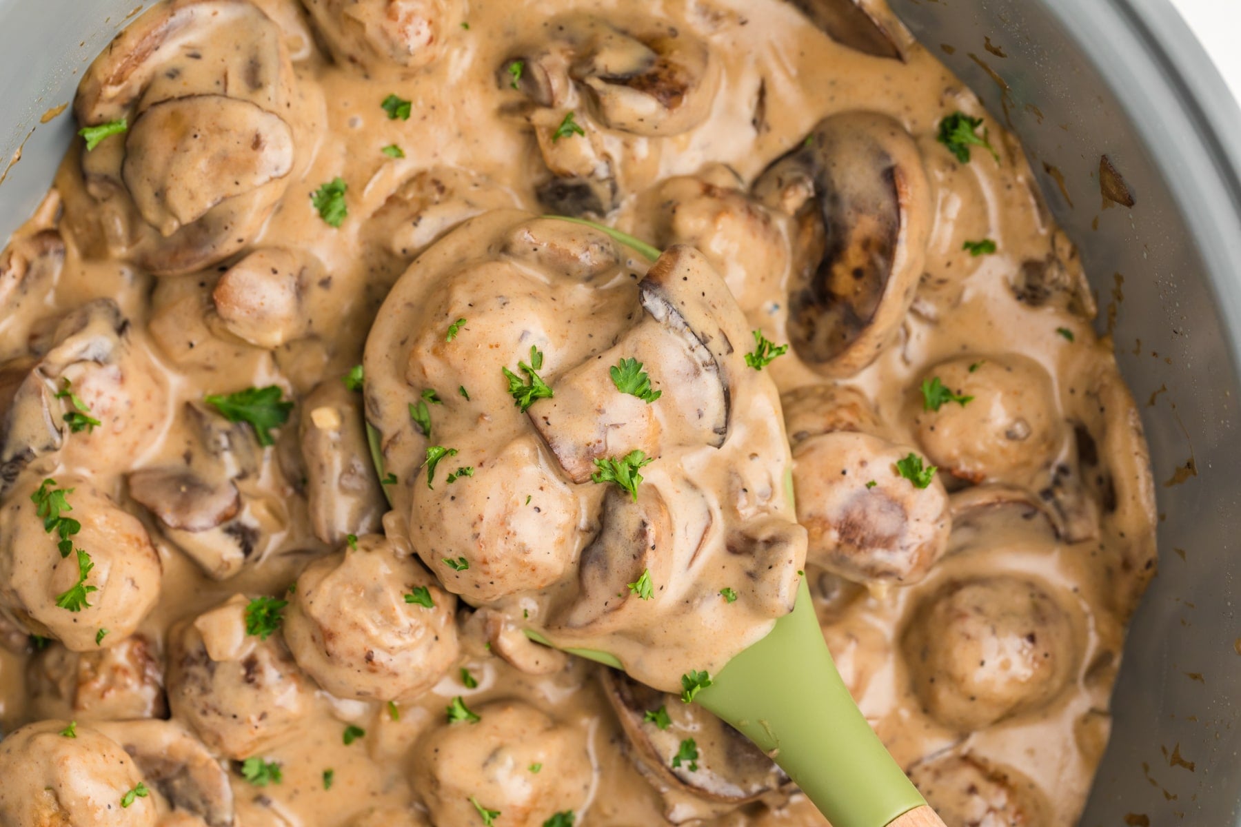 Taking a spoonful of mushroom stroganoff from a skillet.