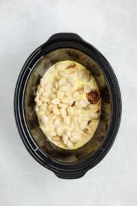 Adding gnocchi to a slow cooker along with meatballs and a cream sauce.