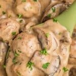 A spoonful of meatballs in a cream sauce with mushrooms.
