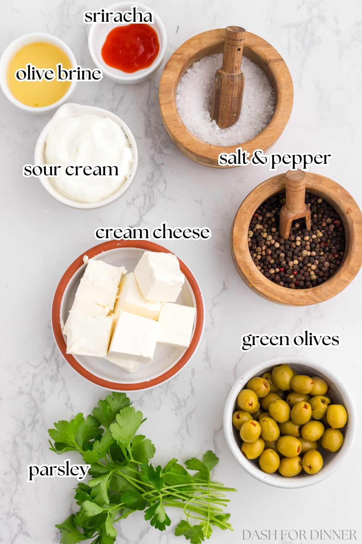 The ingredients needed to make olive dip, including cream cheese, sour cream, and green olives.