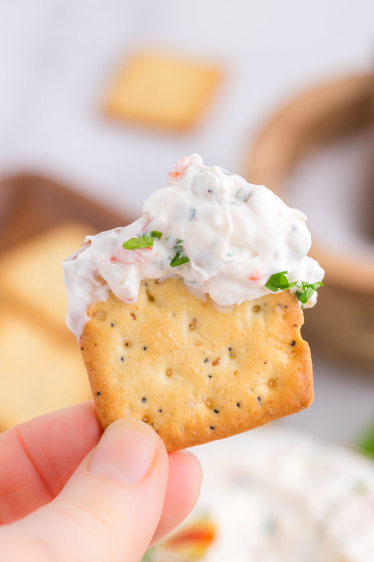 A cracker dipped into a creamy olive dip.