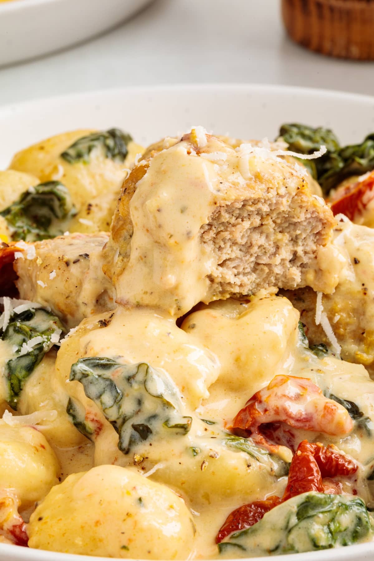 A pile of meatballs and gnocchi with spinach and sun-dried tomatoes.