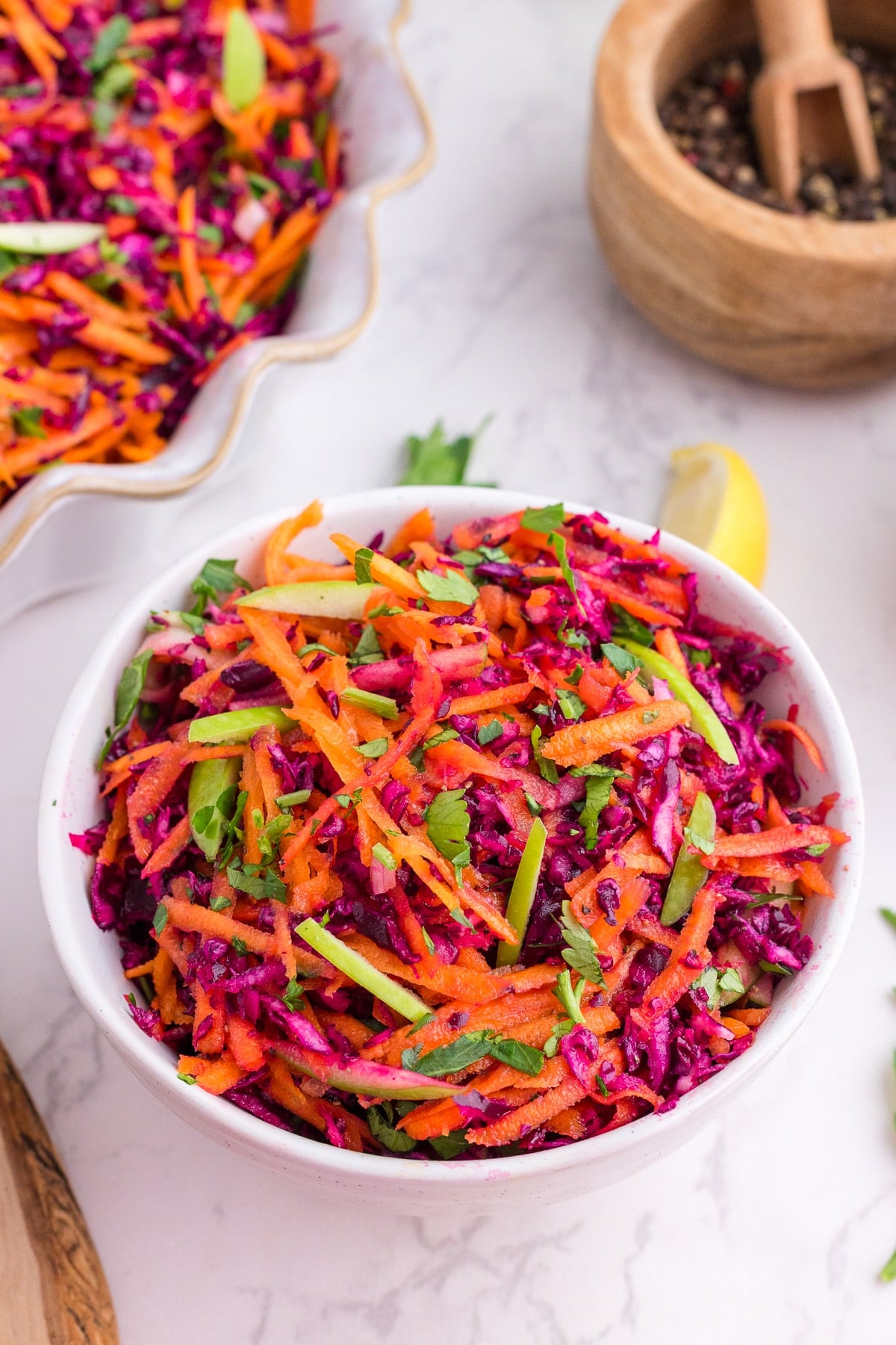 A bowl of cabbage and carrot slaw, garnished with fresh parsley.