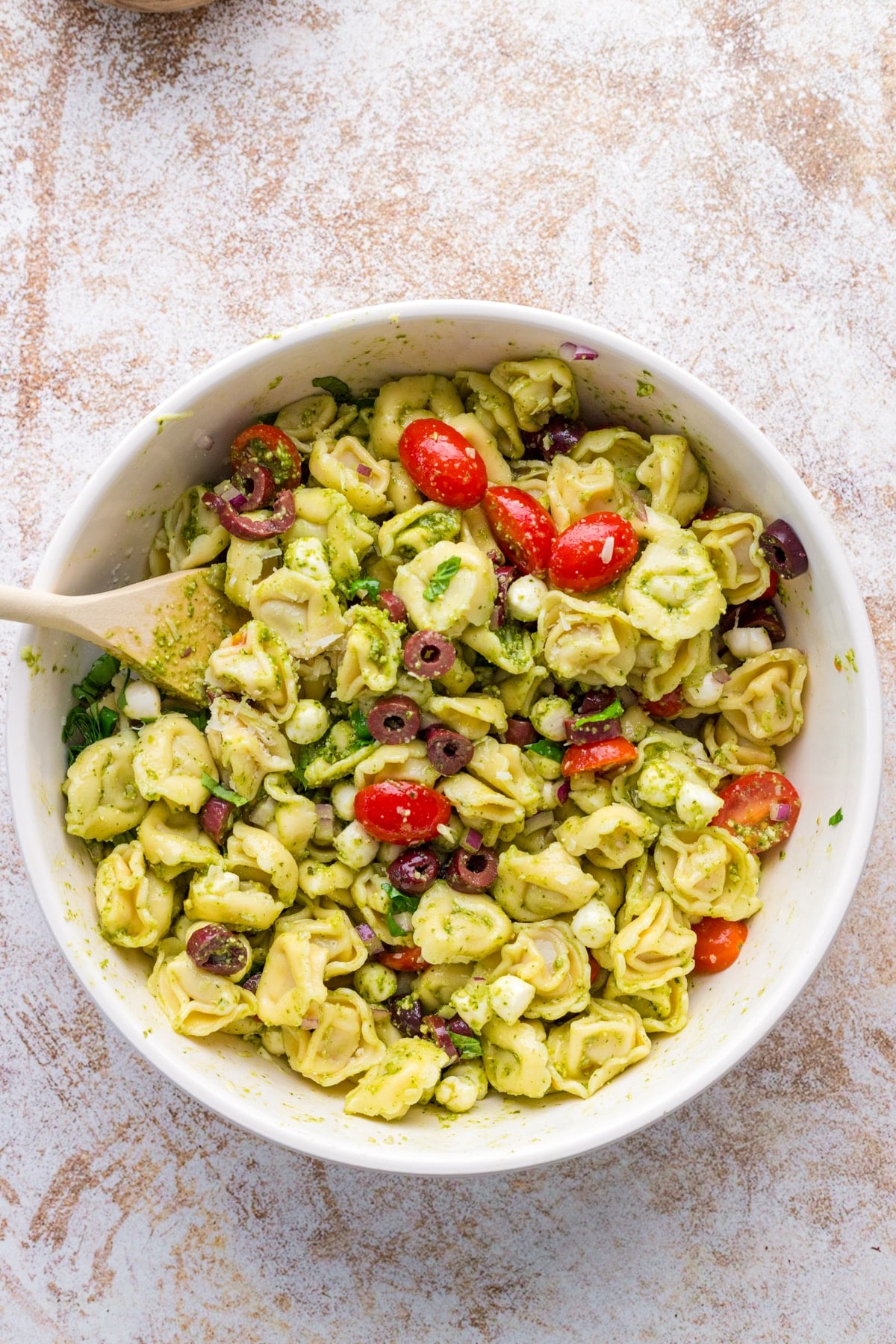 A bowl of cold tortellini salad tossed with basil pesto.