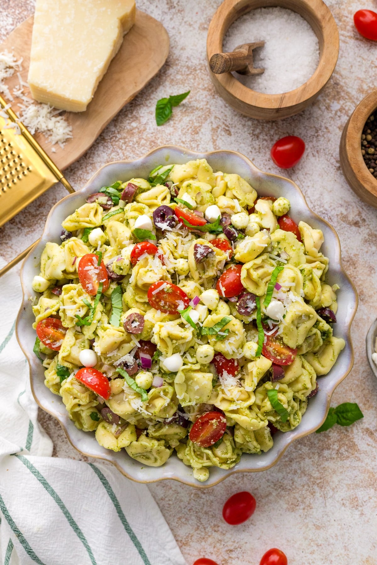 A salad bowl filled with tortellini salad, featuring tomatoes, basil, and mini mozzarella pearls.