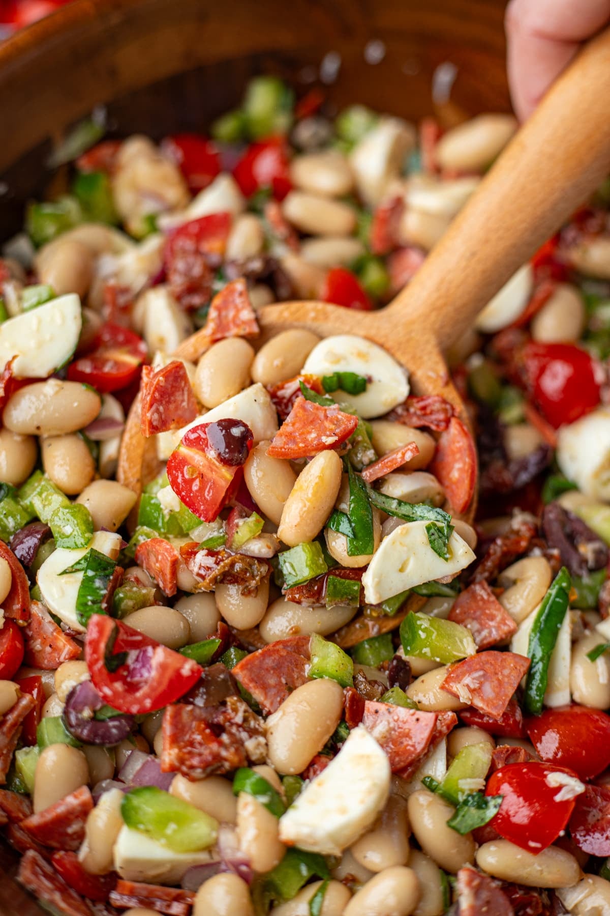 Taking a scoop of bean salad from a wooden bowl.