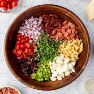 A salad bowl filled with compartments of pasta, mozzarella, green pepper, red onion, pepperoni, etc.