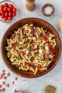 A large bowl filled with pasta salad, featuring fresh mozzarella balls, tomato, and pepperoni.