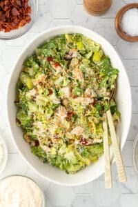 A tossed caesar salad with chicken and bacon.