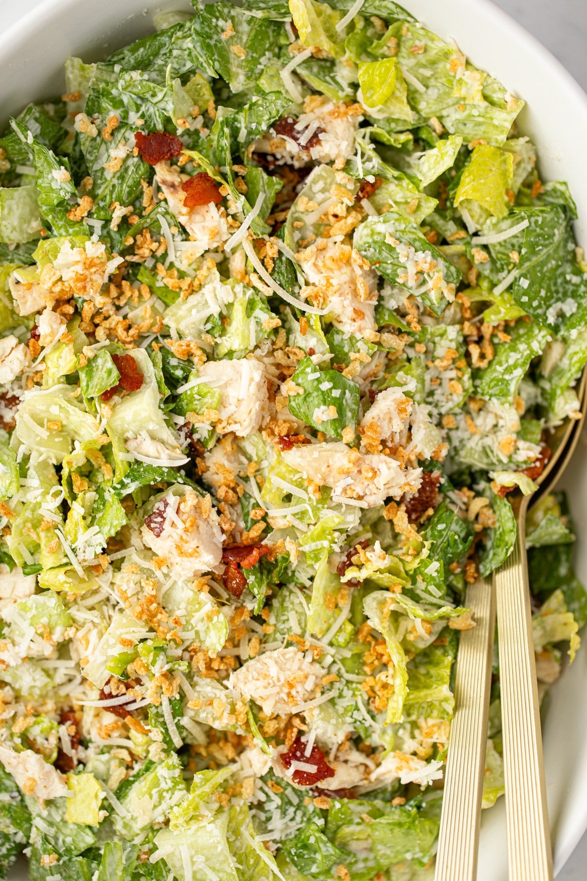 A caesar salad topped with toasted breadcrumbs, bacon, chicken, and parmesan.
