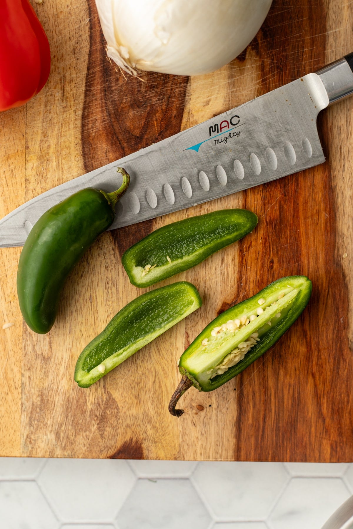 Cutting the sides off of a jalapeno pepper to avoid the pith and seeds.