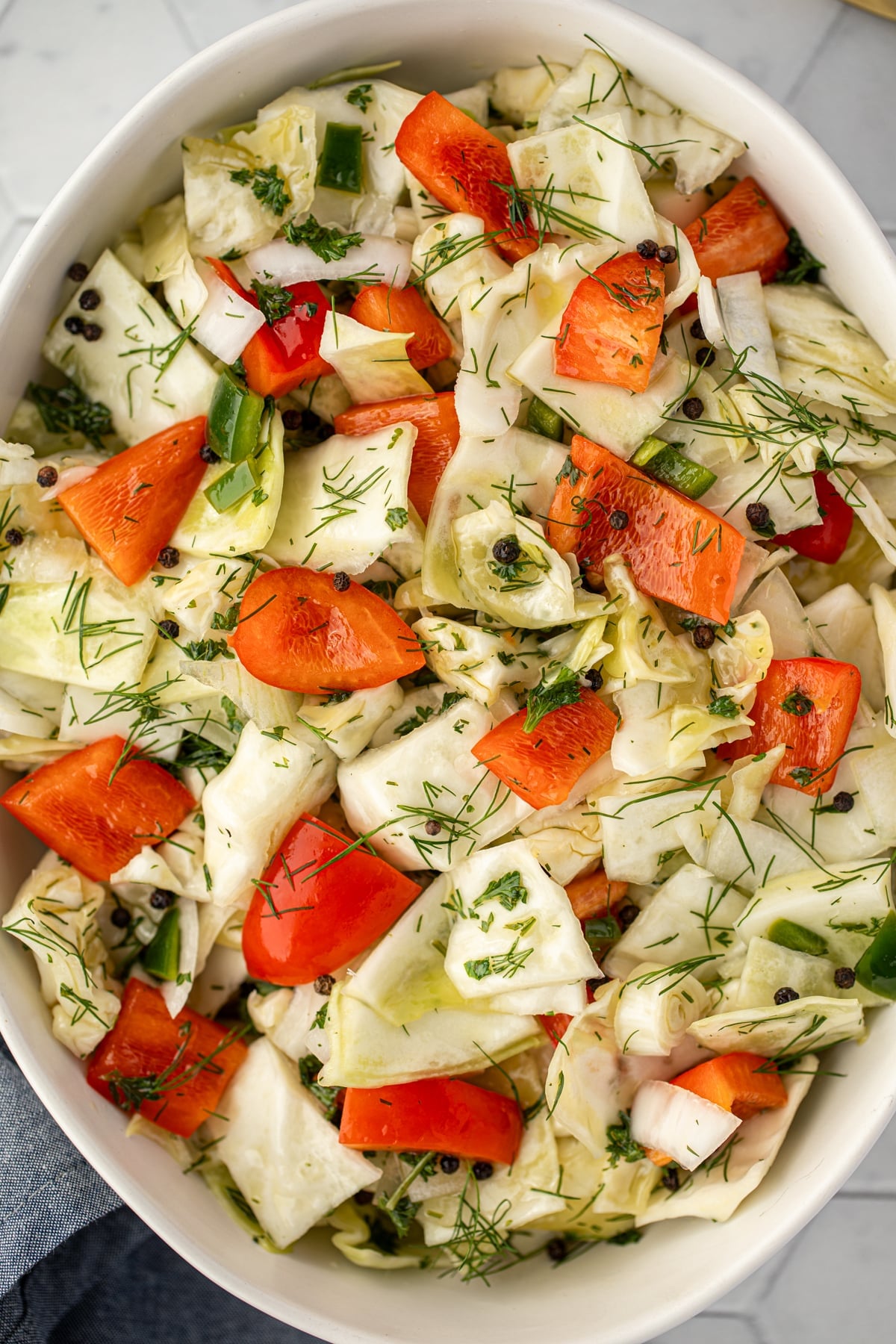 A bowl of pickled cabbage salad with red pepper and dill.