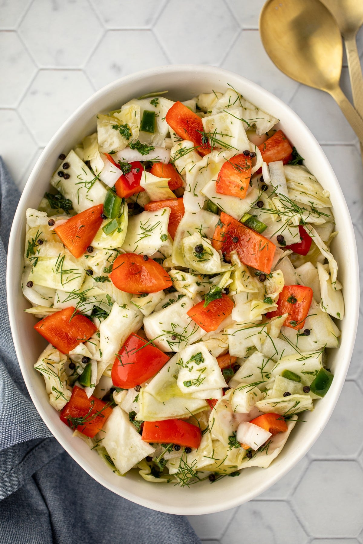 A bowl filled with marinated cabbage salad, featuring red pepper and dill.