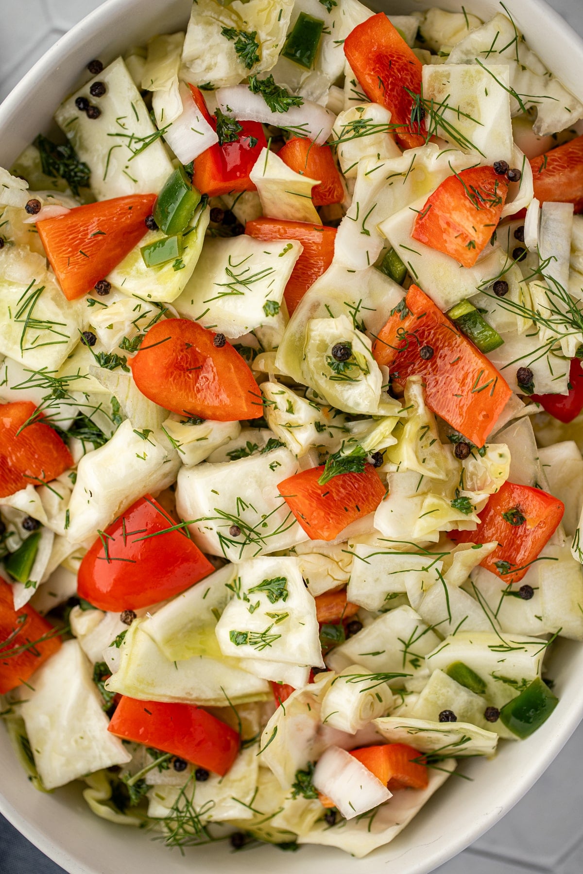 A marinated salad featuring cabbage, red pepper, peppercorns, and fresh dill.